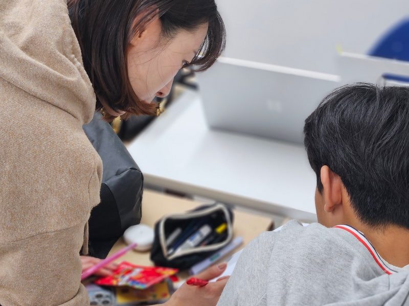 백마·마두 킬영어수학전문학원 수업에서 선생님이 학생 옆에 서서 문제지를 짚어가며 설명하는 모습